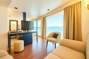 A modern room with a flat-screen TV, a desk, a comfortable sofa, and a large window offering a view of the sea. - Nile Cruise Royal Queen 2 Every Wednesday from Aswan 3 nights and every Saturday from Luxor 4 nights (Aswan)