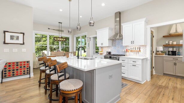 A spacious kitchen with a large island, white cabinetry, and pendant lighting. - New! Lakefront 4BR, Kayaks, Paddleboards, Games (Littleton)