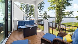 A covered deck with a seating area, a table, and a view of the lake. - New! Lakefront 4BR, Kayaks, Paddleboards, Games (Littleton)