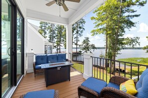 Eine überdachte Terrasse mit Sitzgelegenheit, einem Tisch und Blick auf den See.