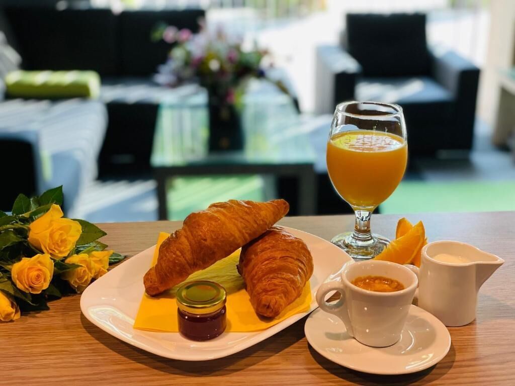 Uma mesa com croissants, um copo de suco de laranja e uma xícara de café para o café da manhã.