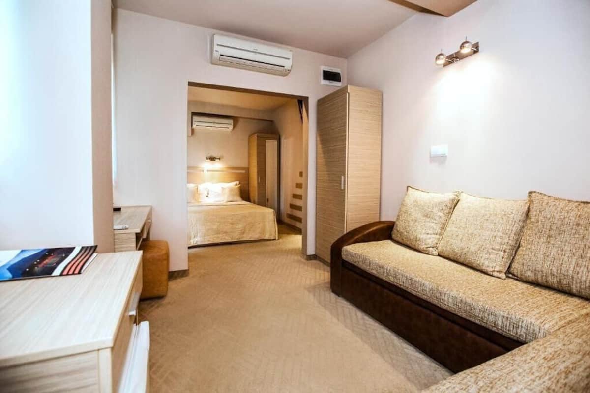 Habitación de hotel pequeña con cama, sofá, escritorio y armario.
