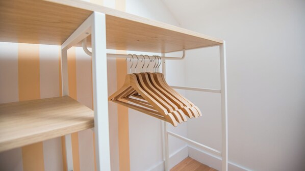 Une armoire en bois avec plusieurs étagères et une tringle pour suspendre les vêtements.
