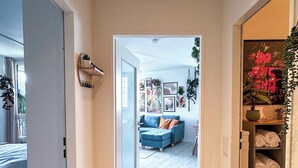 A hallway with a blue sofa, a wooden floor, and a door leading to a room with a bed. - Hejm Mountain Vibe & Design vacation apartment - 2 min to the bike park and ski slope (Winterberg)