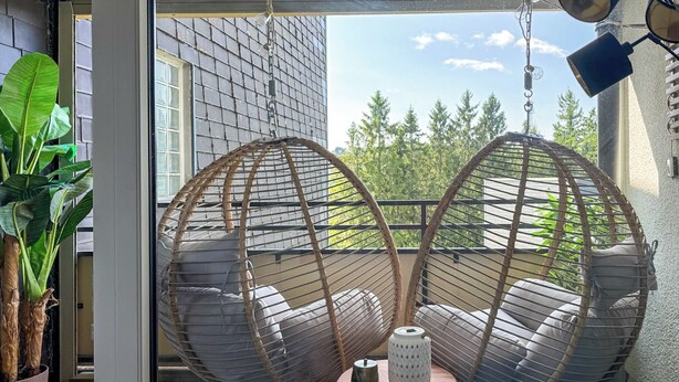 A room with two hanging chairs, a potted plant, and a small table with a vase. - Hejm Mountain Vibe & Design vacation apartment - 2 min to the bike park and ski slope (Winterberg)