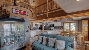 A cozy living area with a teal sofa, a glass display case with various items, and a wooden ceiling.