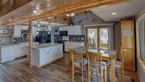 A spacious kitchen with wooden cabinets, a dining area with a table and chairs, and a large window providing natural light.