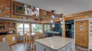 A kitchen with wooden cabinets, a central island, and a dining area with chairs.