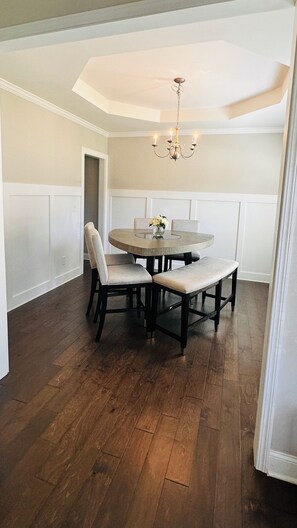A dining area with a round table, four chairs, and a chandelier. - Casa Aluna, World Cup FIFA Retreat Sleeps 10 (Dacula)