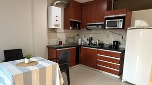 A compact kitchen with wooden cabinets, a microwave, a stove, and a refrigerator.