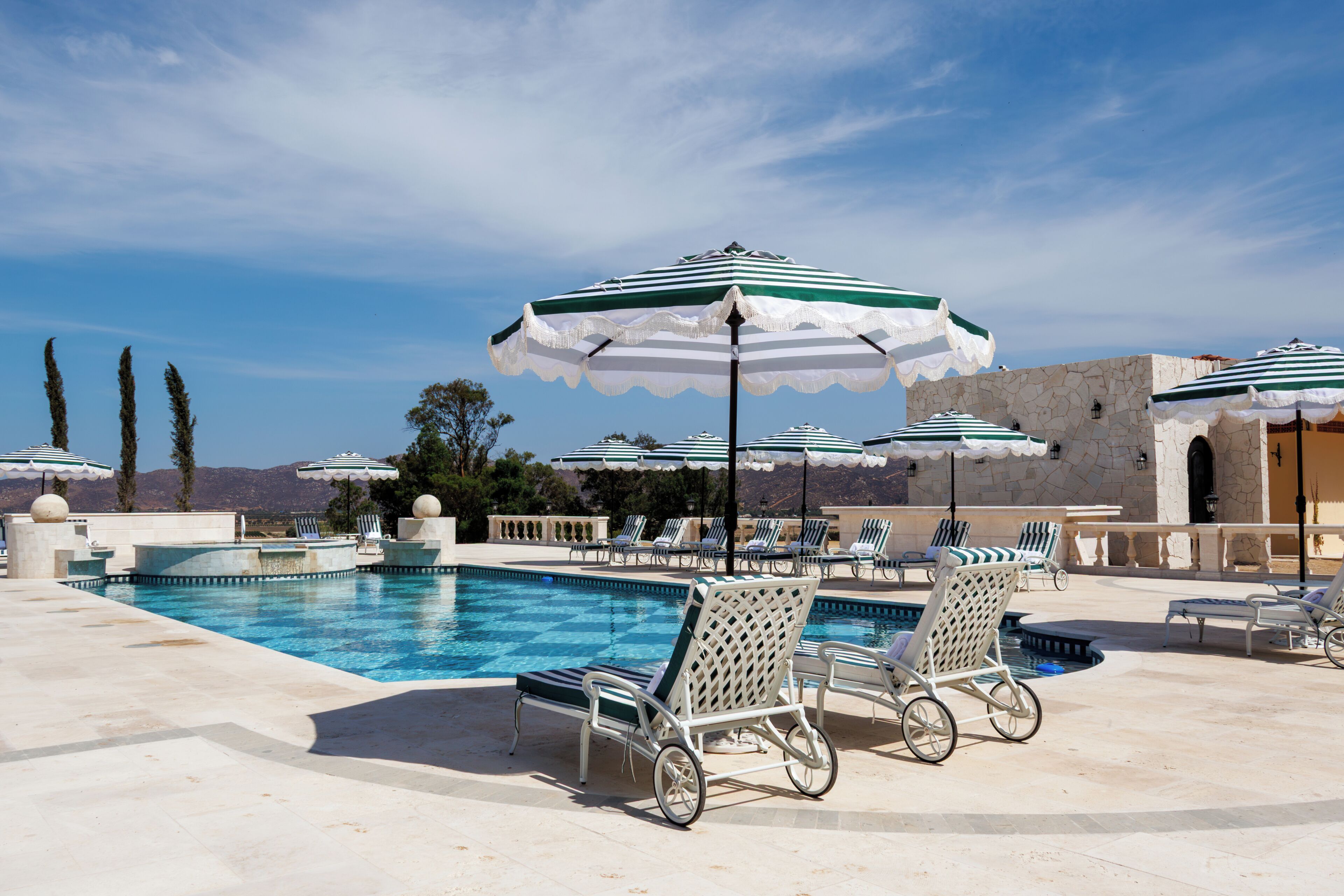 Una piscina al aire libre, sombrillas, sillones reclinables de piscina