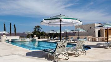 Una piscina al aire libre, sombrillas, sillones reclinables de piscina