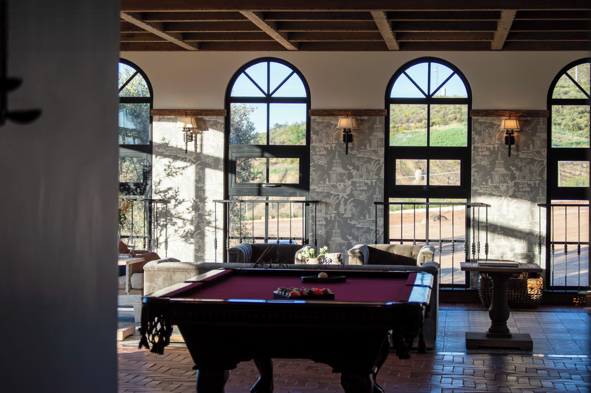 Una mesa de billar en una habitación con ventanas de arco y paredes de piedra.