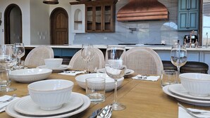 Un coin repas avec une table en bois mise pour le repas, comprenant des assiettes, des bols et des couverts blancs.