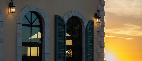 A building with multiple windows, some with shutters, and a balcony with a railing.
