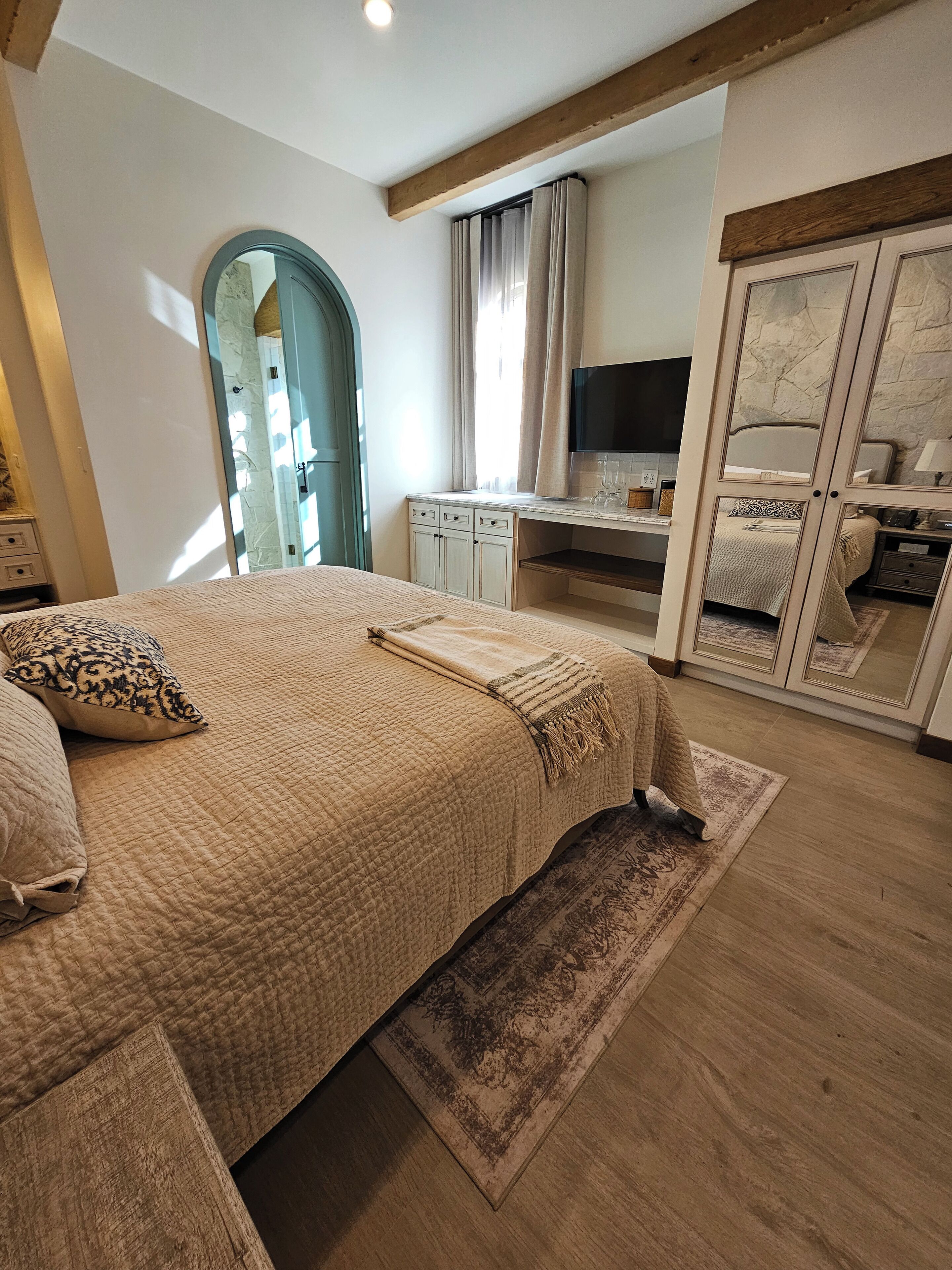 Une chambre avec un grand lit, un bureau, une télévision et une armoire.
