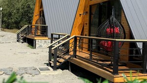 Δύο ξύλινα σπιτάκια με μεταλλικές στέγες, το καθένα με ξύλινη βεράντα και μια σκάλα που οδηγεί στην είσοδο.