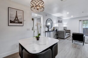 A modern living room with a marble dining table, a grey sofa, and a black chair.