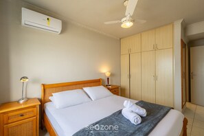 A bedroom with a bed, nightstands, a ceiling fan, an air conditioner, and a wardrobe. - Apt w/ Balcony and Oceanfront View in BC - Ipc0901 (Balneário Camboriú)