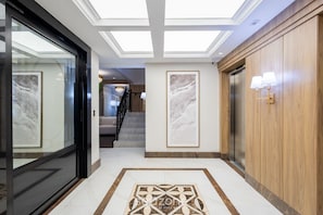 A hotel lobby with a glass entrance, a central staircase, and a patterned floor. - Apt w/ Balcony and Oceanfront View in BC - Ipc0902 (Balneário Camboriú)