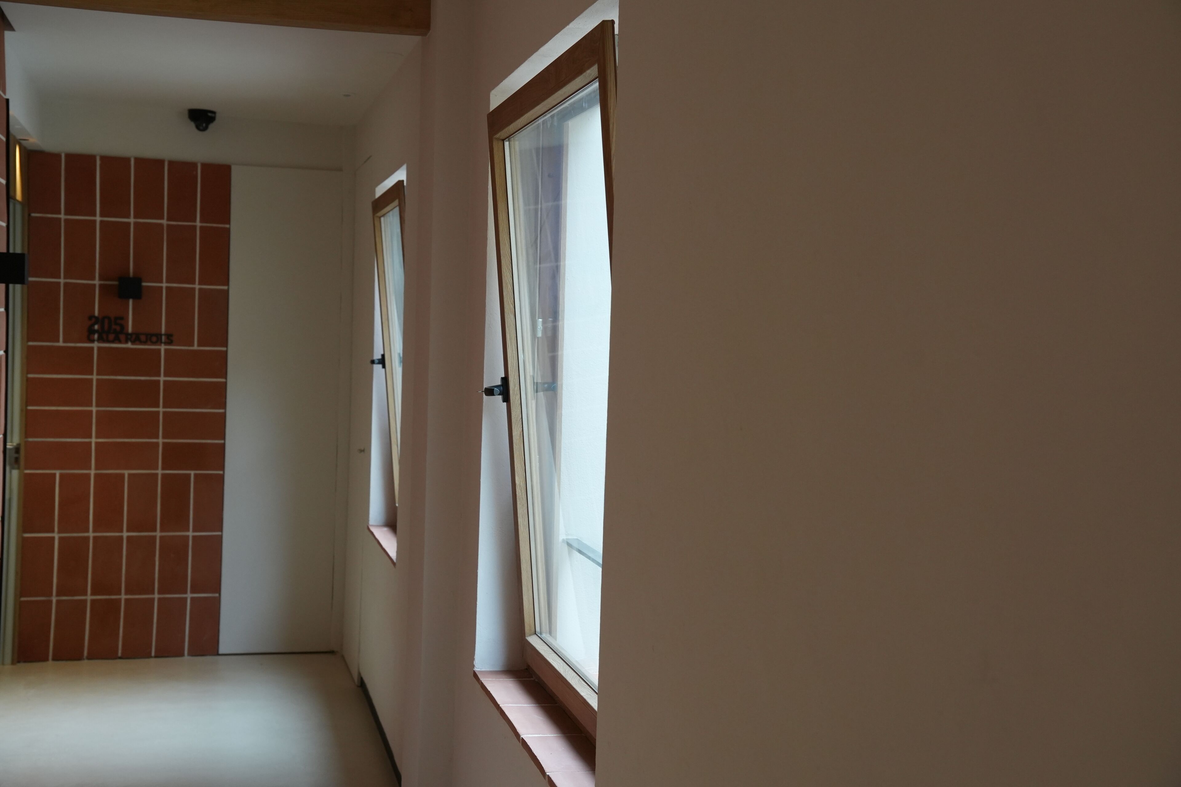 Un pasillo estrecho con paredes de azulejos y una puerta que indica “205 Blackwoods”.