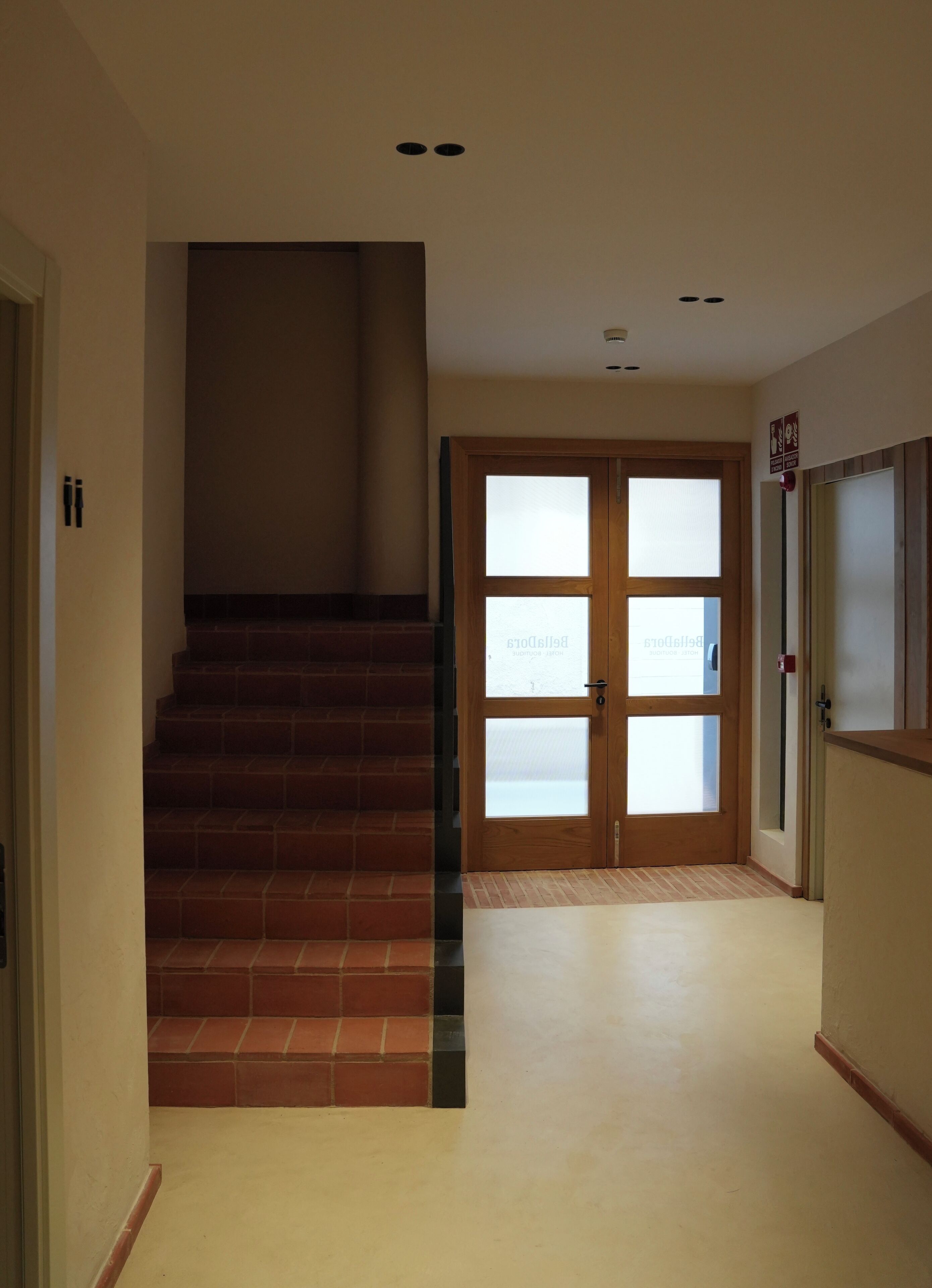A hallway with a wooden staircase leading to a door with frosted glass panels.