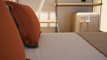 A modern hotel room with a bed, a white wall, and a small white appliance labeled "CREATE".