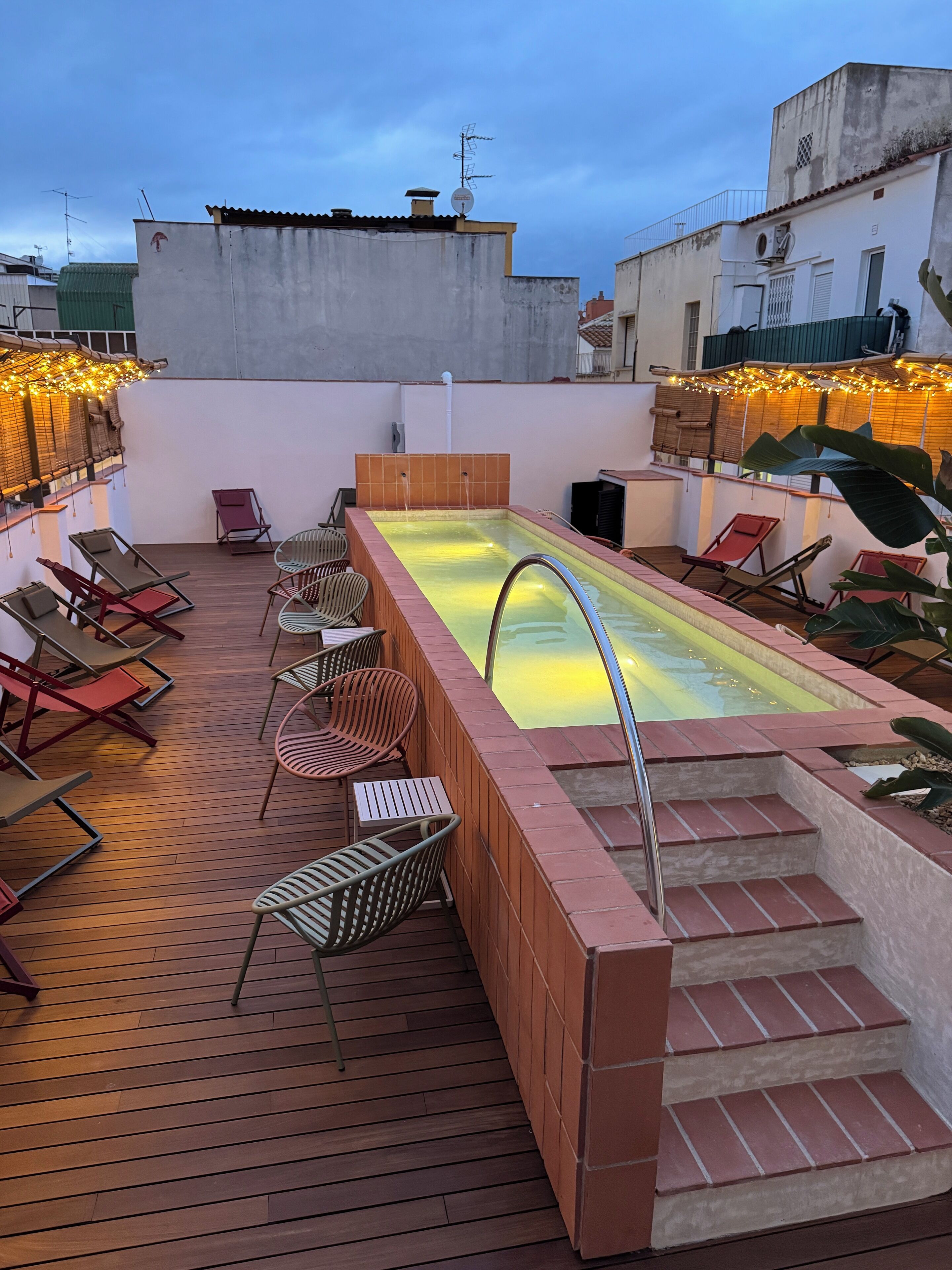 Un espace piscine aménagé sur le toit, avec des chaises longues et un petit escalier menant à la piscine.