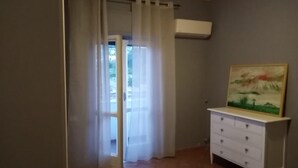 Una habitación con puerta de vidrio corredera, un aparador blanco y un cuadro en la pared.