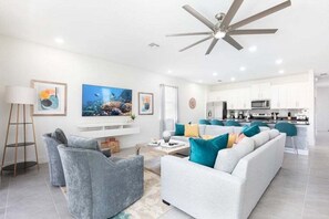 A modern living room with a sofa, armchairs, a coffee table, and artwork on the walls.