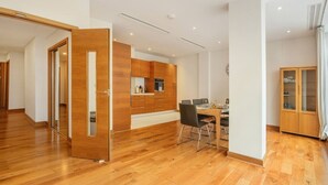Een moderne keuken met houten kastjes, een eethoek met een tafel en stoelen, en een kast met glazen deuren.