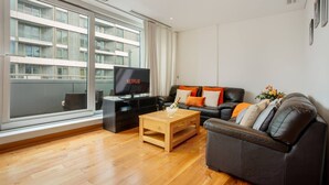 Een moderne woonkamer met een groot raam, een flatscreen televisie, een leren bank en een houten salontafel.