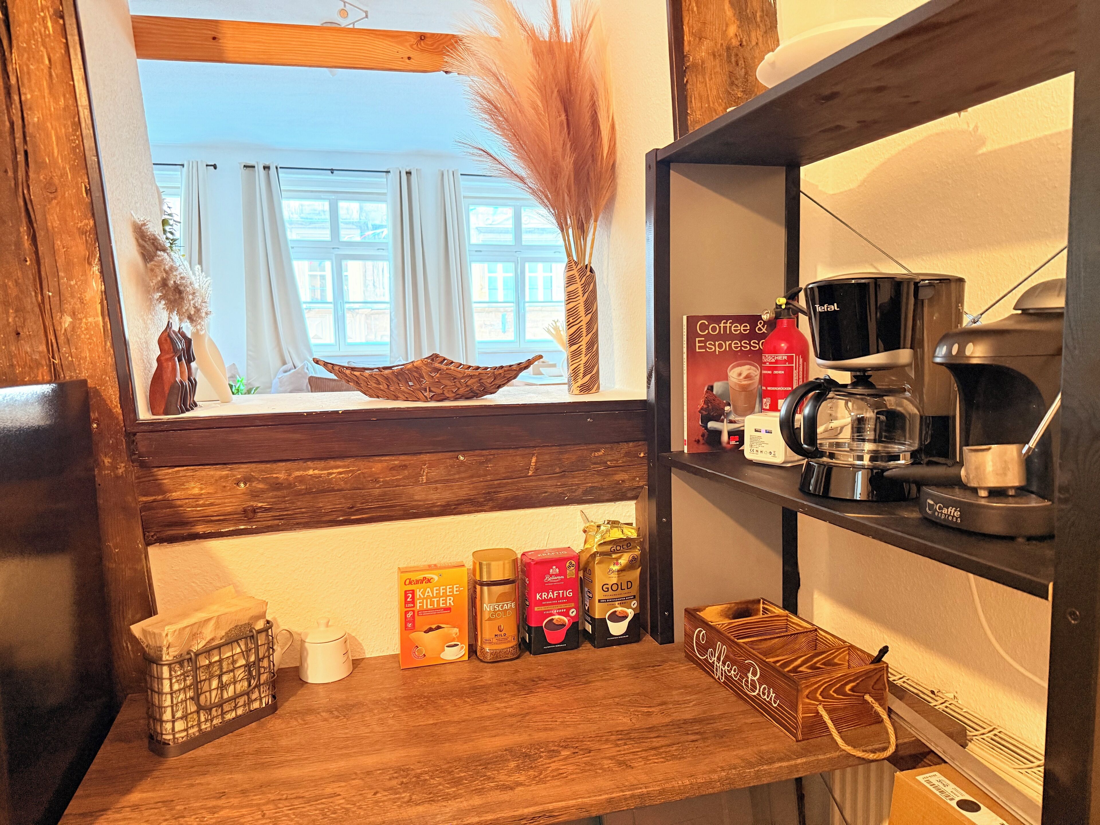 Eine Küchenzeile mit einer Kaffeestation, inklusive Kaffeemaschine, Kaffeekapseln und Kaffeefilter.