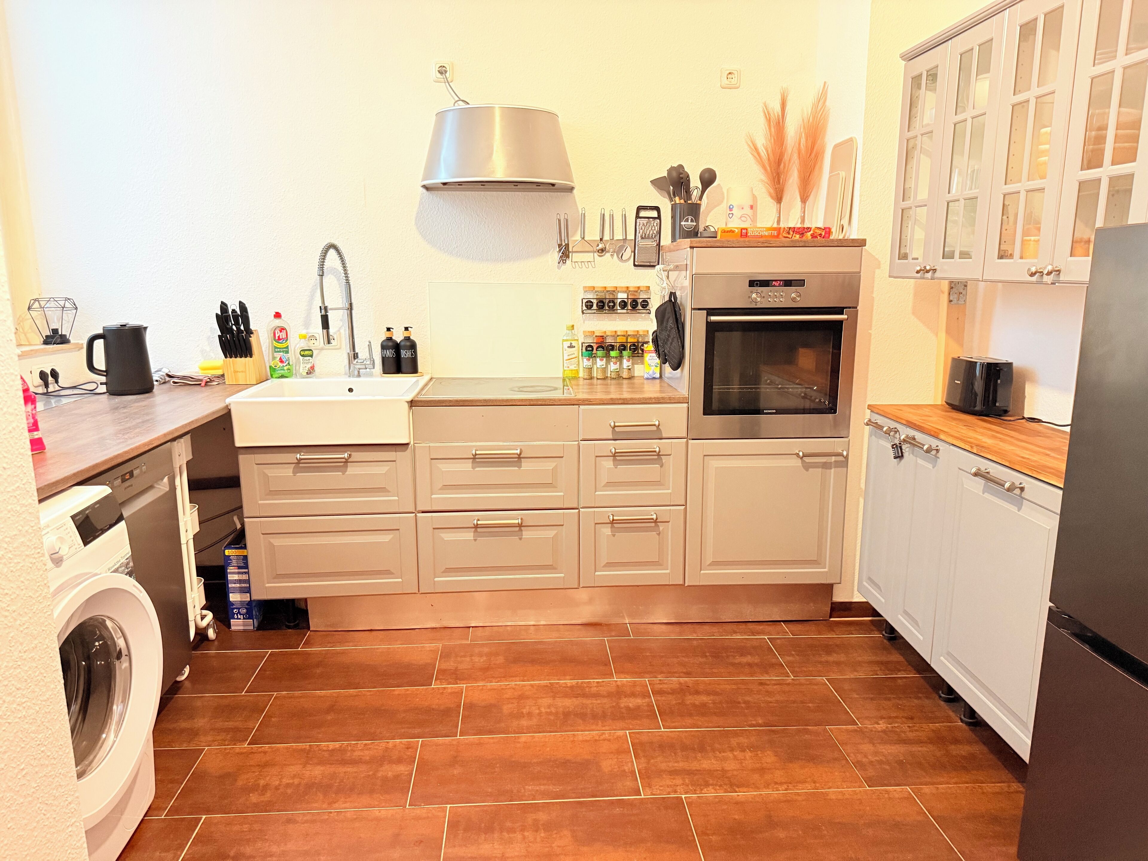 Una cocina compacta con lavadora, horno empotrado y cafetera.