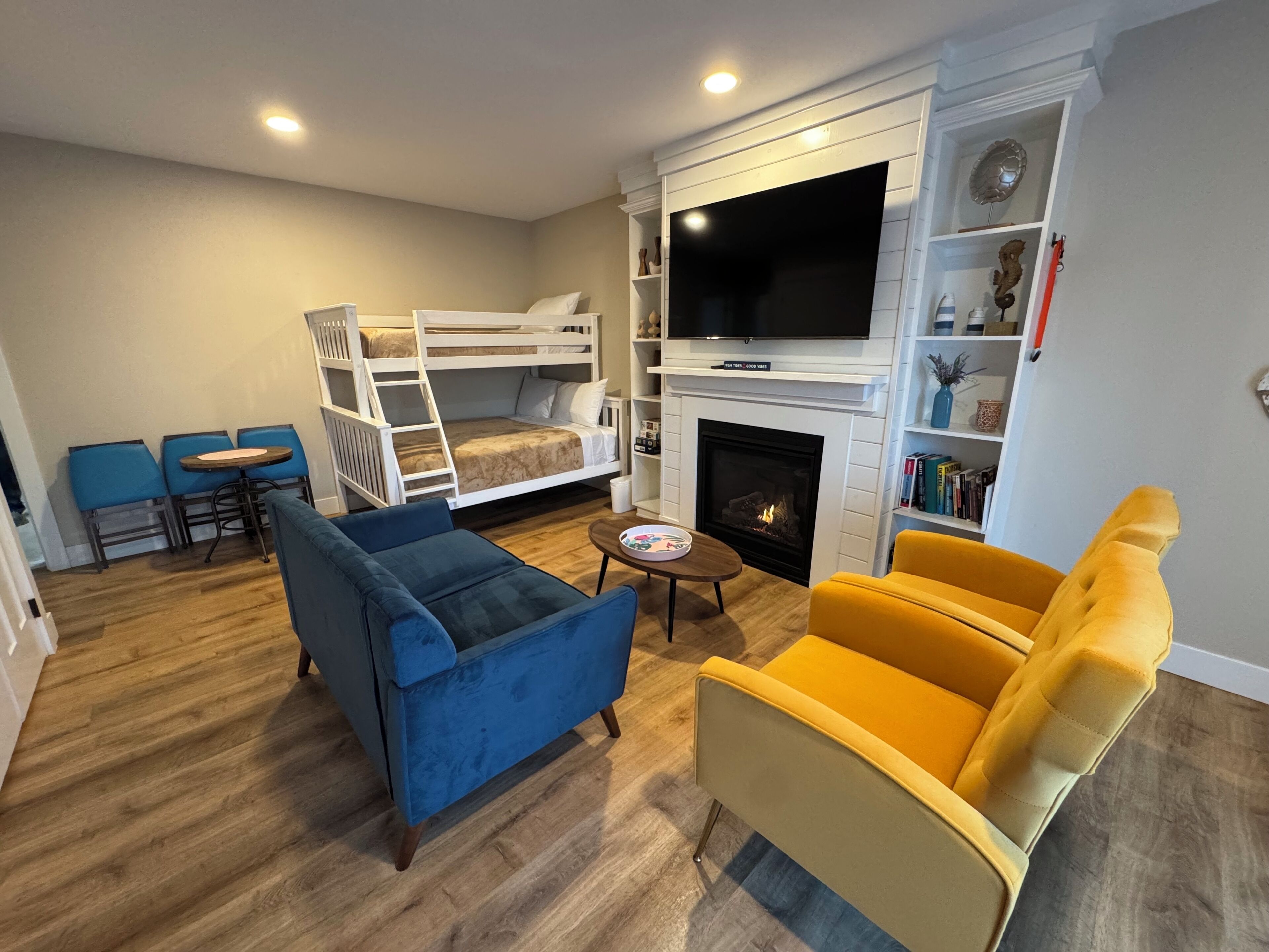Una sala de estar con una litera, un sofá, un sillón amarillo, una chimenea y un televisor.