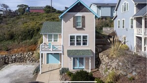 A two-story house with a front porch, a stone retaining wall, and a small front yard.