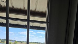 A window with a view of a lake, grassy areas, and a metal structure. - Cozy Cottage With a View in La Grange (La Grange)