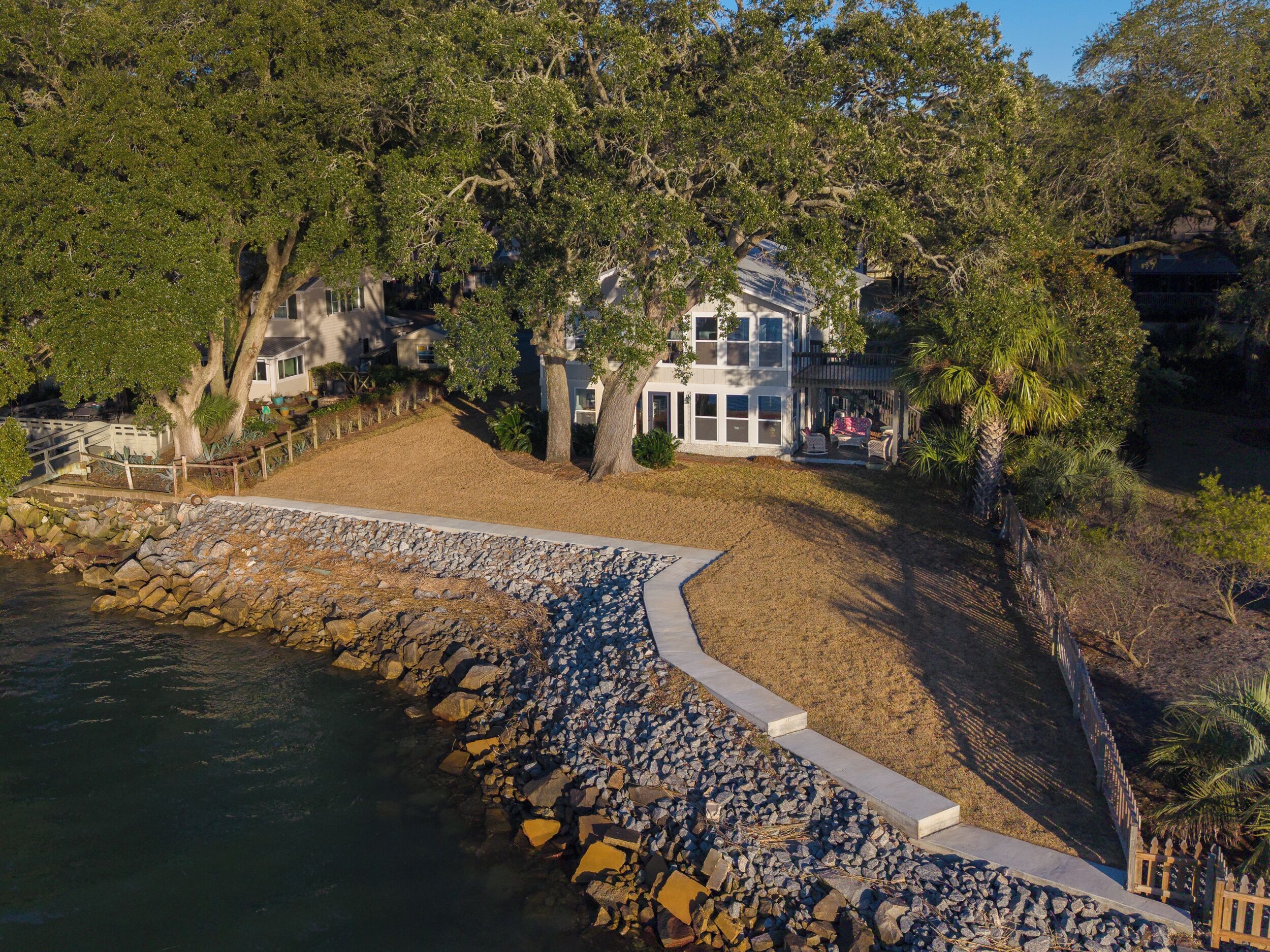 A coastal property with a stone pathway leading to a house surrounded by trees.