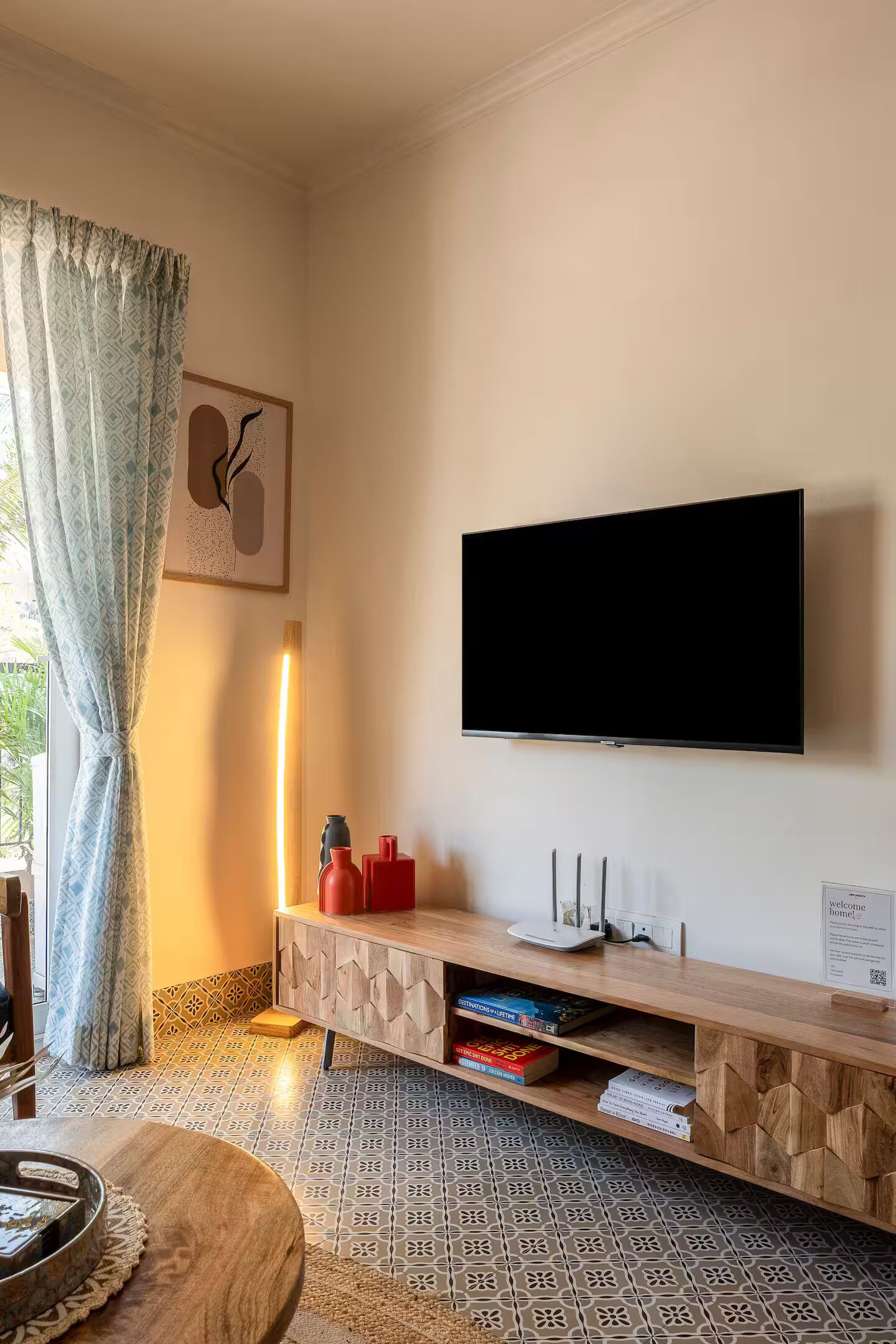 Un soggiorno moderno con televisore a schermo piatto, mobile TV in legno, pavimento a motivi decorativi e una zona pranzo con tavolo rotondo.