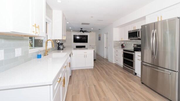 Una cocina moderna con armarios blancos, electrodomésticos de acero inoxidable y piso de madera.