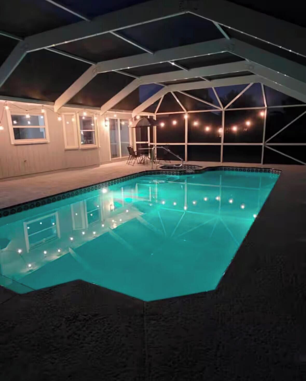 A swimming pool with a geometric roof structure and string lights.