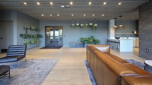 A modern interior with a reception area, seating, and a kitchen. - Skyline Views from Nashville Penthouse – Pool & Minutes to Broadway (Nashville)