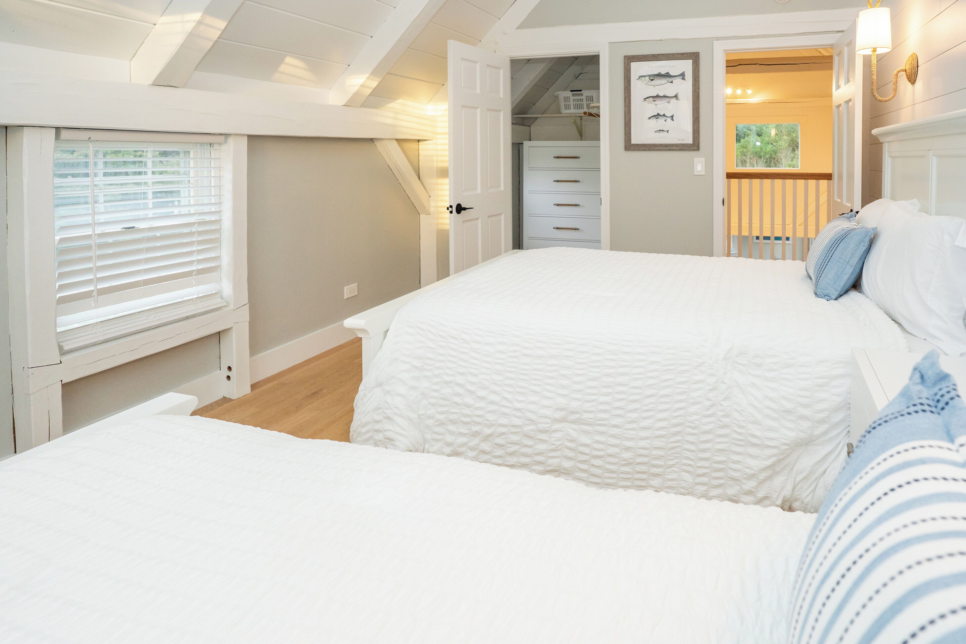A bedroom with a large bed, a walk-in closet, and a view of the outdoors.