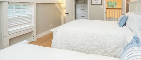 A bedroom with a large bed, a walk-in closet, and a view of the outdoors.