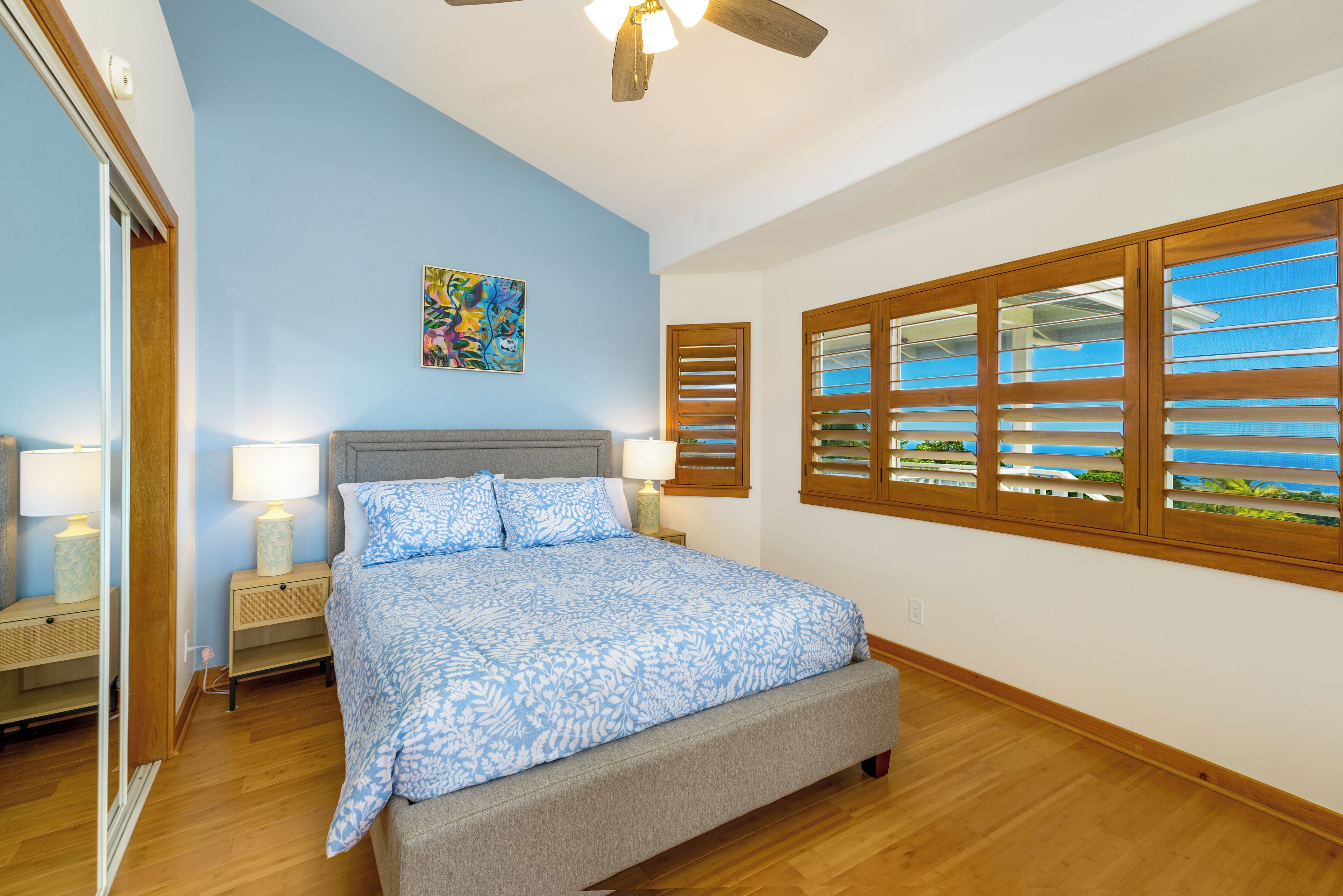 A bedroom with a bed, nightstands, a ceiling fan, and a window with blinds.