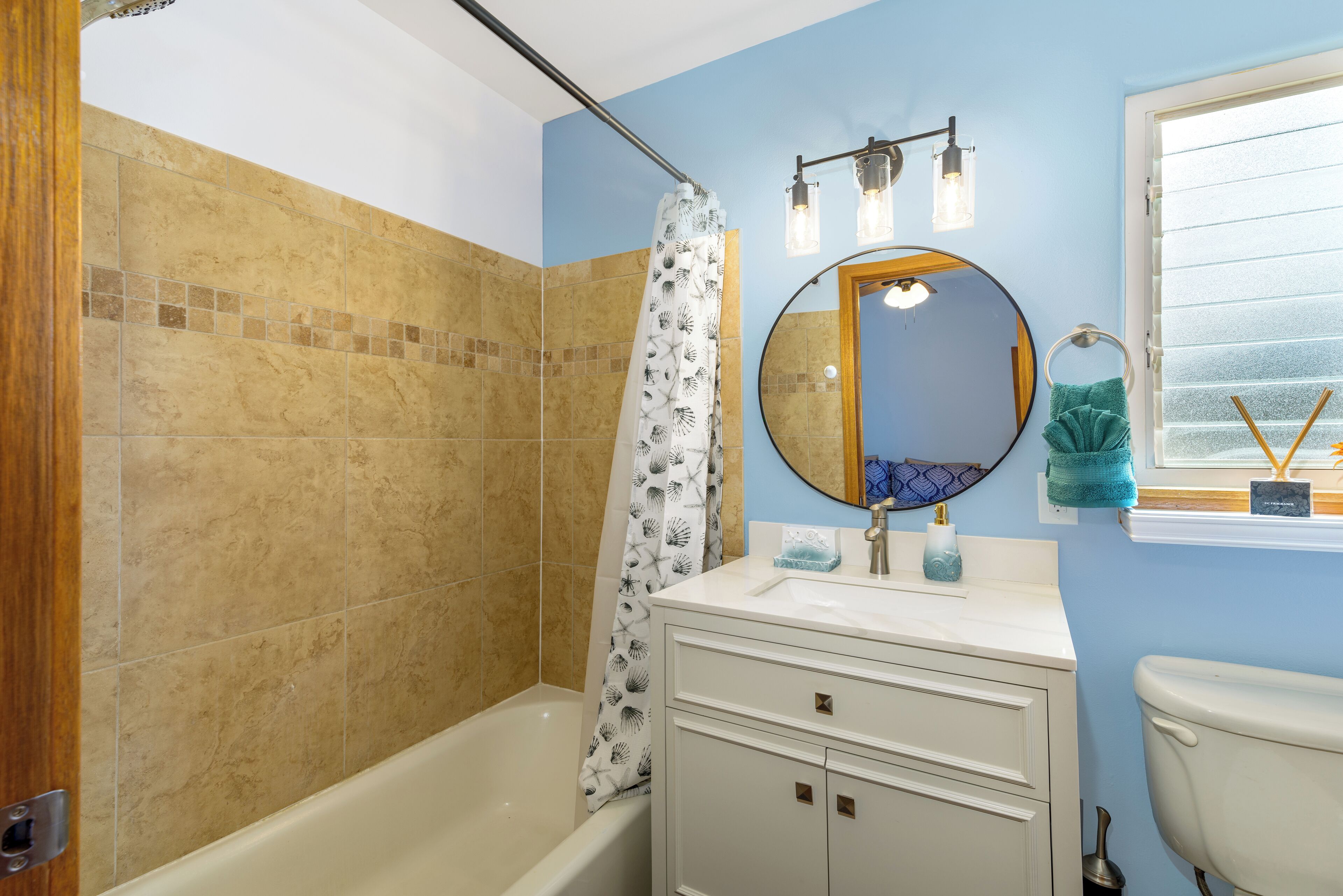 A bathroom with a bathtub, a sink with a mirror, and a toilet.