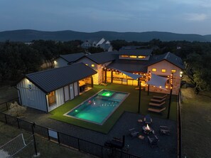 Propiedad residencial con piscina, mobiliario exterior y vista a colinas distantes.