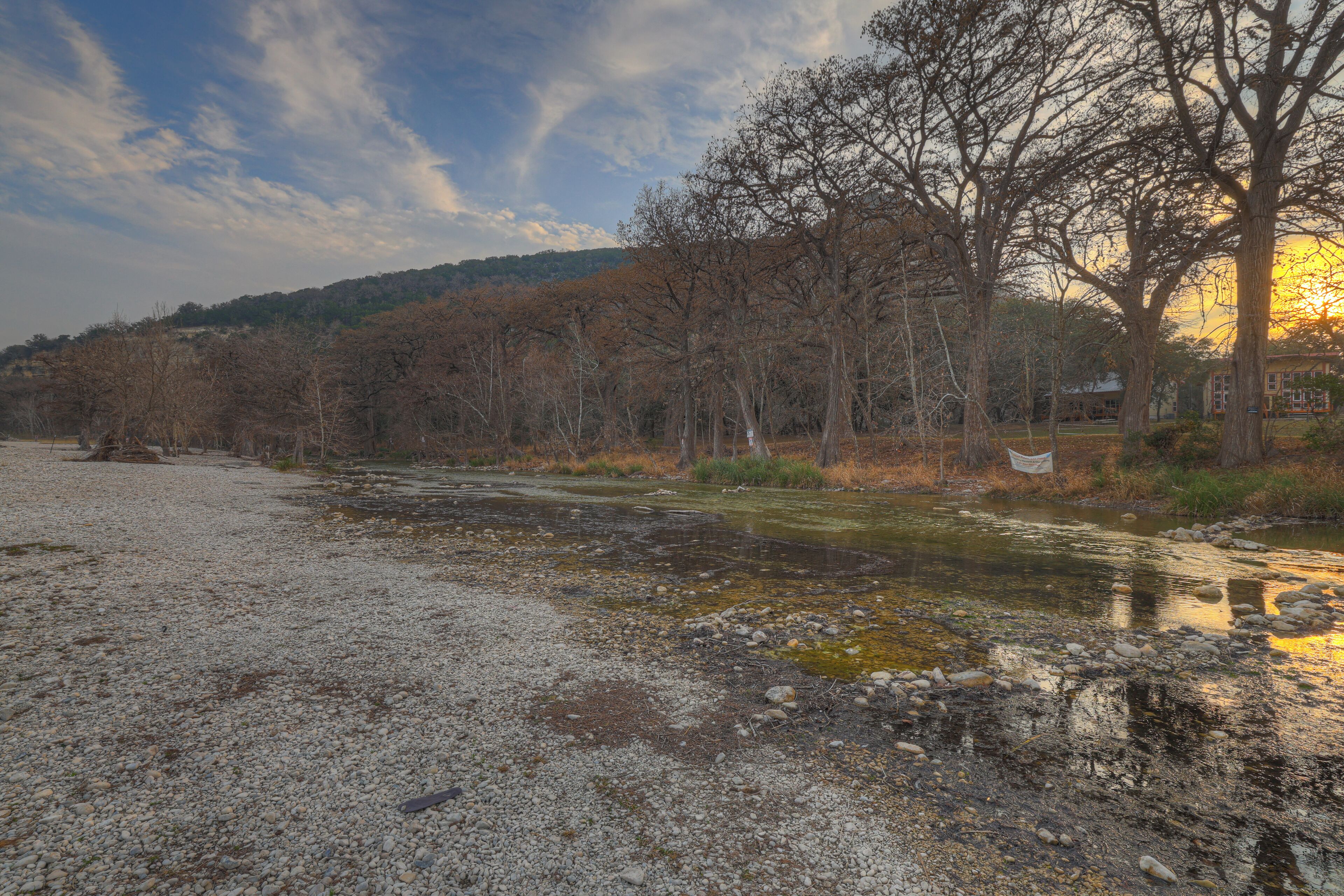 Une rivière avec des galets et des arbres en arrière-plan.