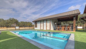 Une piscine avec une terrasse en bois et un espace salon couvert.