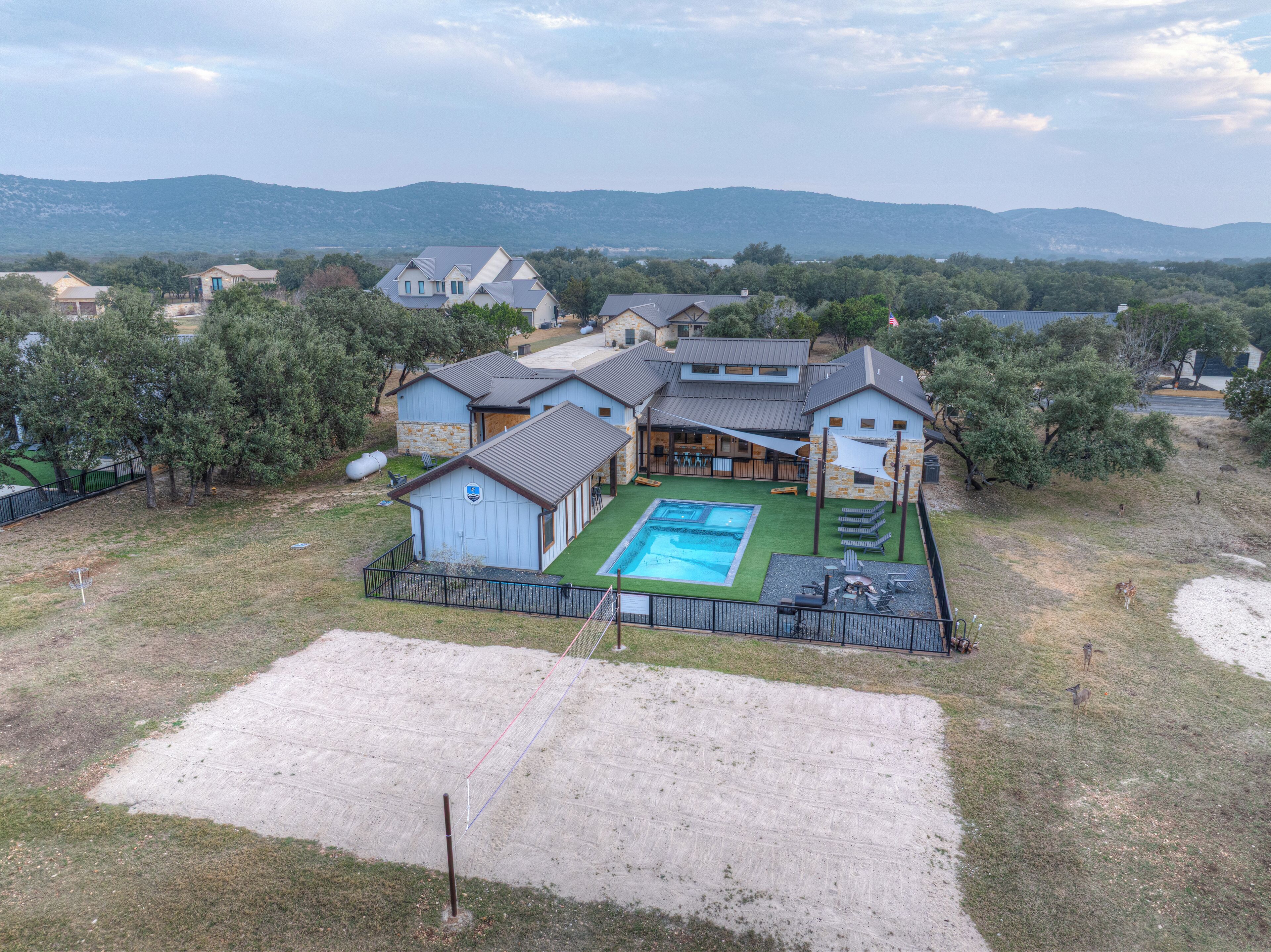 A large house with a swimming pool, a fenced yard, and a view of mountains.